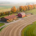 Vue miniature façon tilt-shift d'une petite piste de courses attelées à la campagne en automne, avec un pavillon, une grange rouge et des écuries
